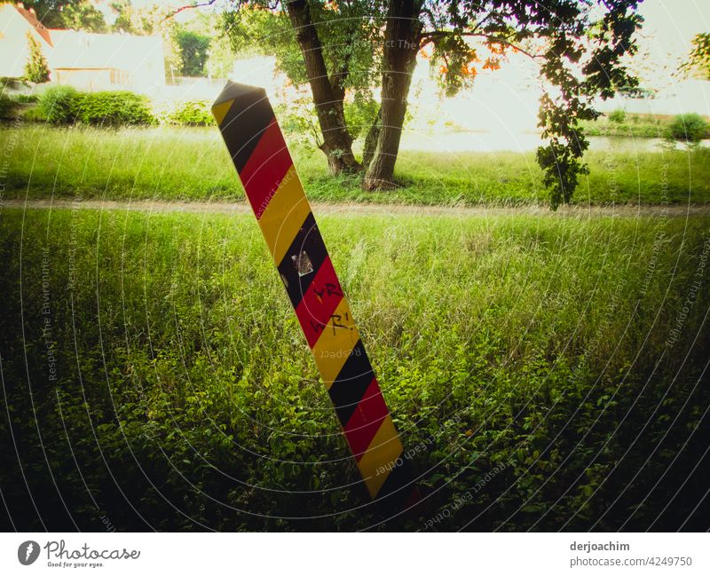 The border post at the river, the Neiße, Germany - Görlitz / Poland, stands quite crooked on the green meadow. goerlitz Pole Park Nature Forest Colour photo