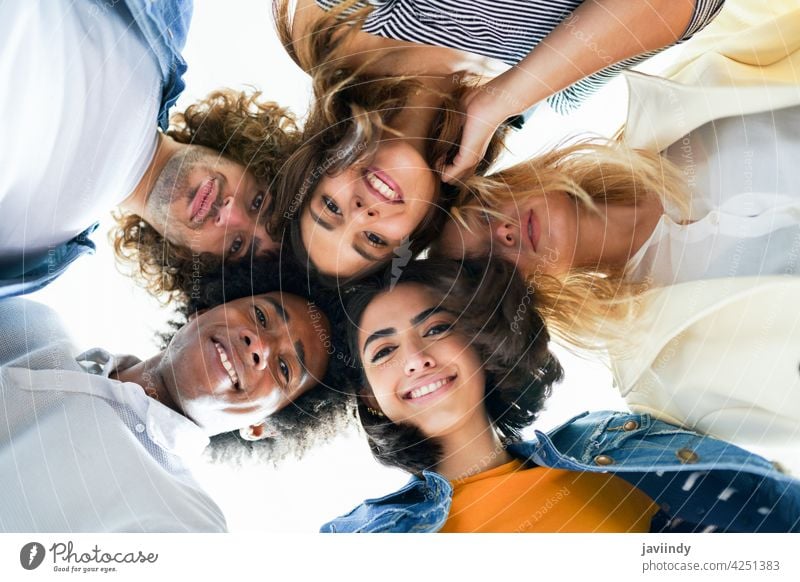 Multi-ethnic group of friends with their heads together in a circle. people young multi-ethnic multiracial diversity lifestyle outdoors portrait women laughing