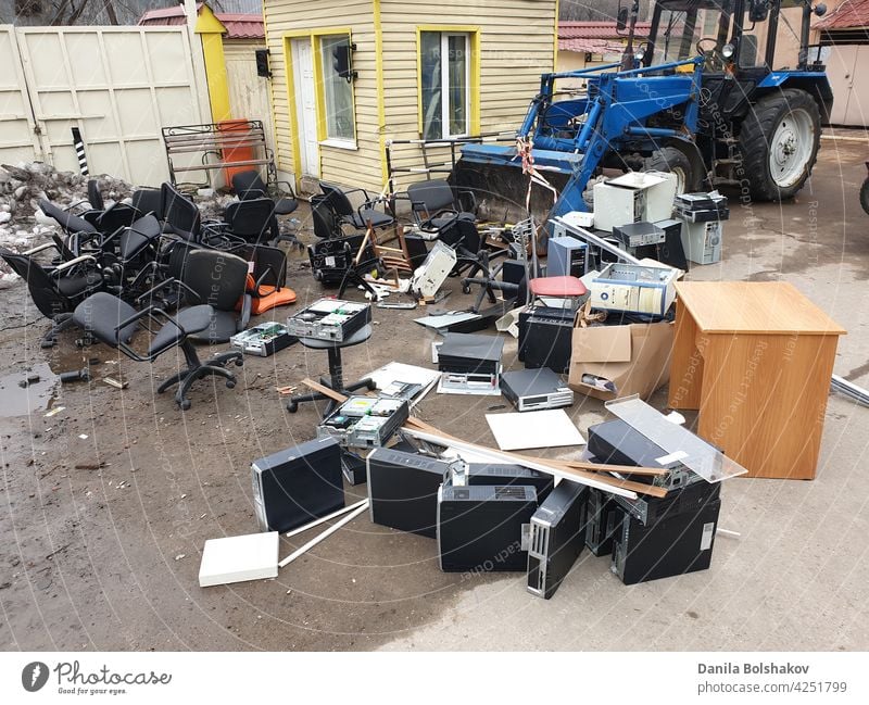 discarded obsolete system units from computers with old office chairs in trash electronic equipment recycle scrap waste parts technology environment plastic