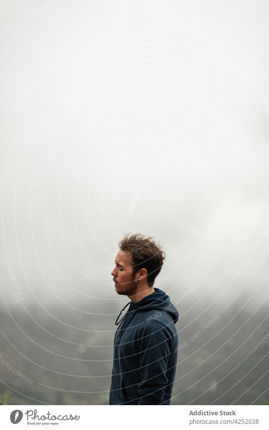 Wistful man standing on hilltop on misty day hiker mountain highland wistful fog thoughtful terrain overcast seville nature traveler trekking rock adventure