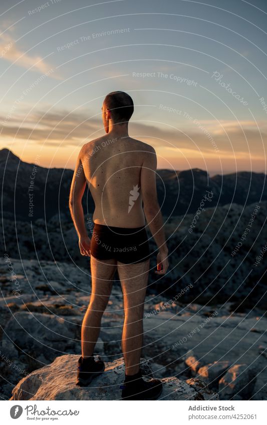 Unrecognizable man in trunks standing on rough mountain peak hiker admire highland underpants range sunset spectacular nature scenery amazing ridge sundown