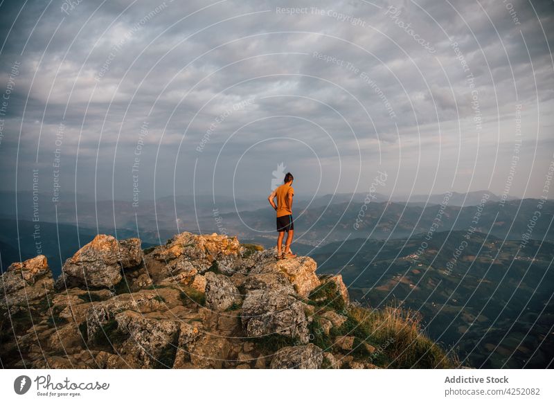 Traveler on high peak of mountain man traveler valley observe viewpoint cloudy overcast nature wanderlust freedom ridge explore hill rock admire adventure stone