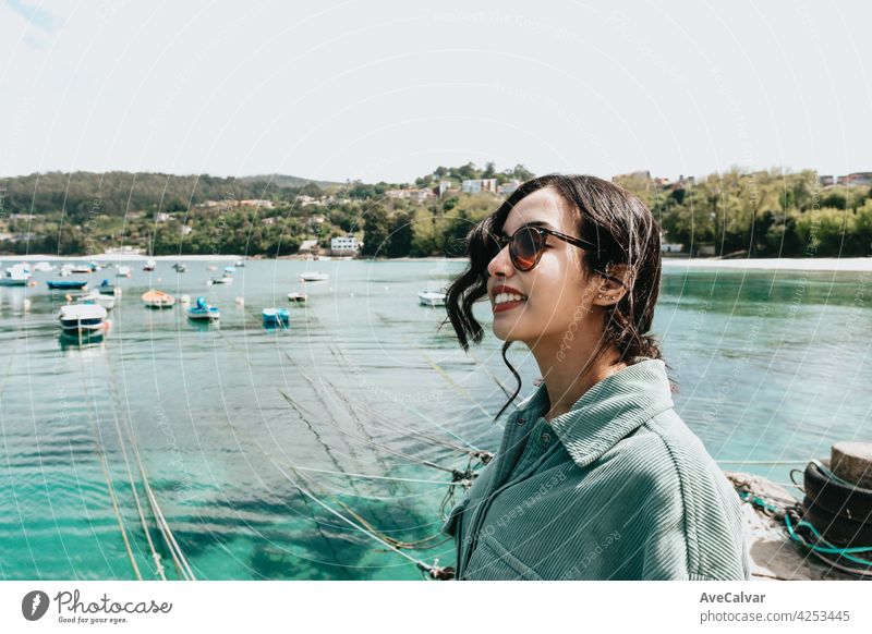 Young woman in a boat dock smiling during a sunny day while using sunglasses beach day person female portrait alone glamour joy sunlight yacht young brunette