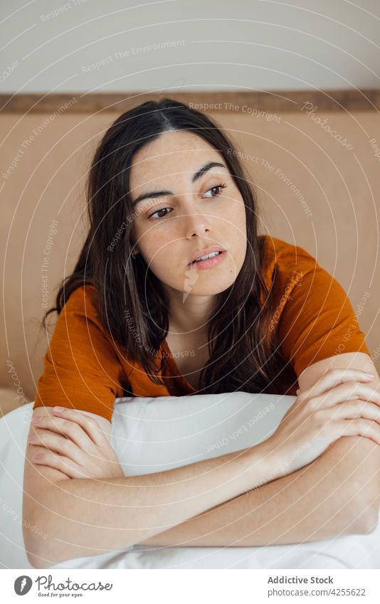 Dreamy woman sitting on comfortable bed in morning dreamy bedroom content positive peaceful serene lifestyle attractive brunette tender thoughtful gentle