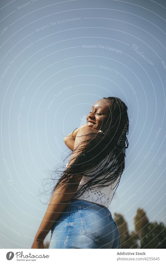 Happy black woman standing on sunny street style fashion happy carefree mood summer town enjoy casual female african american smile trendy outfit flying hair