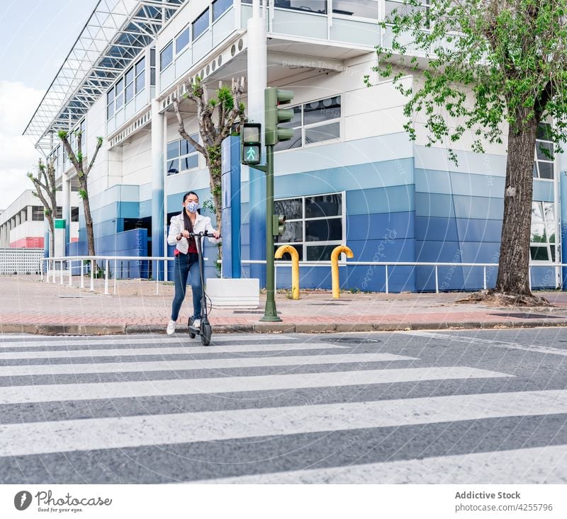 Ethnic riding electric scooter on crosswalk woman ride road covid mask prevent female covid 19 covid19 coronavirus zebra street pandemic new normal epidemic