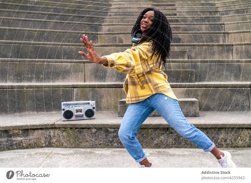 Black woman listening to music and dancing enjoy song boombox entertain cool positive female blaster portable retro old fashioned cheerful casual young