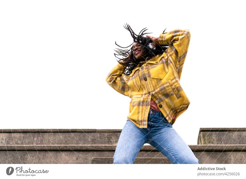 Energetic black woman dancing on concrete border carefree shake dance move leisure freestyle dynamic motion enjoy female action posture millennial smile