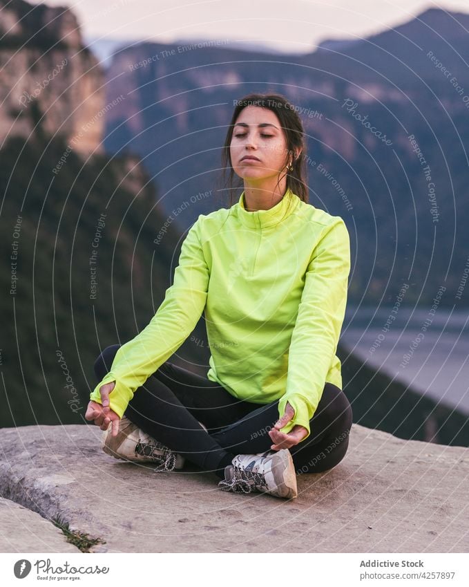 Young Hispanic lady meditating in Lotus pose on cliff edge in rocky canyon woman lotus pose padmasana meditate eyes closed yoga mindfulness nature harmony calm