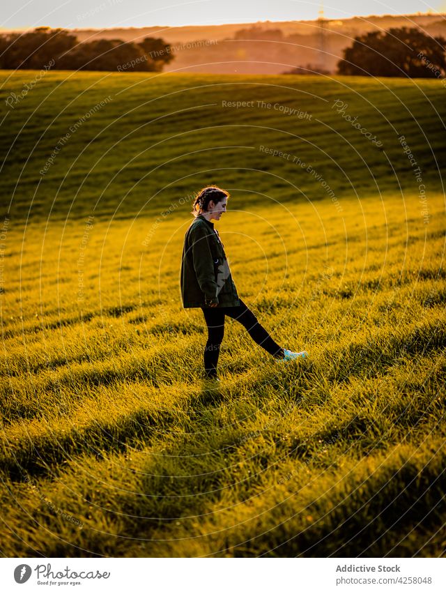 Woman walking on lush grassland at sunset woman stroll meadow nature countryside sundown sunlight field rural season evening twilight summer green casual lawn