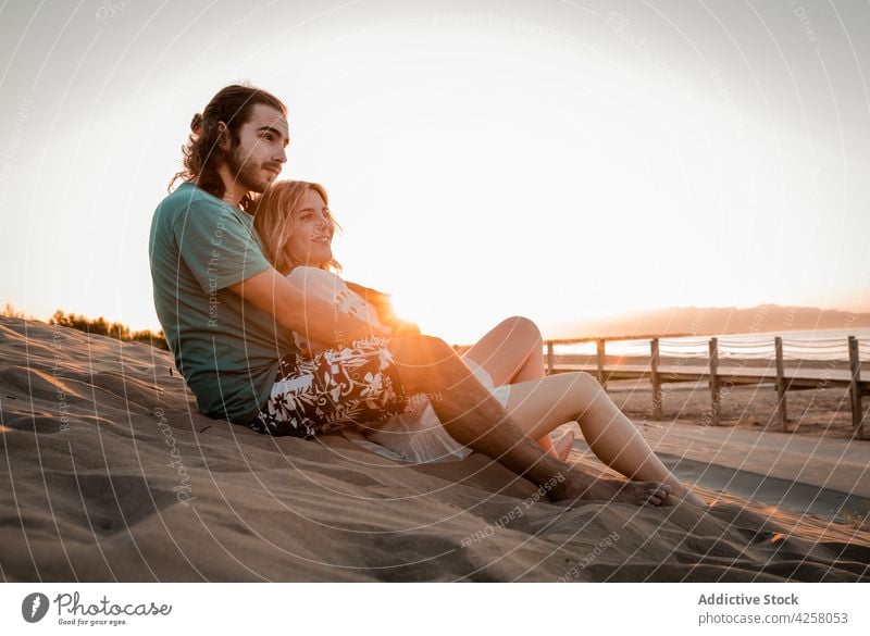 Romantic couple embracing and lying on sandy beach at sunset hug serene seashore embrace romantic love relationship relax summer together vacation nature