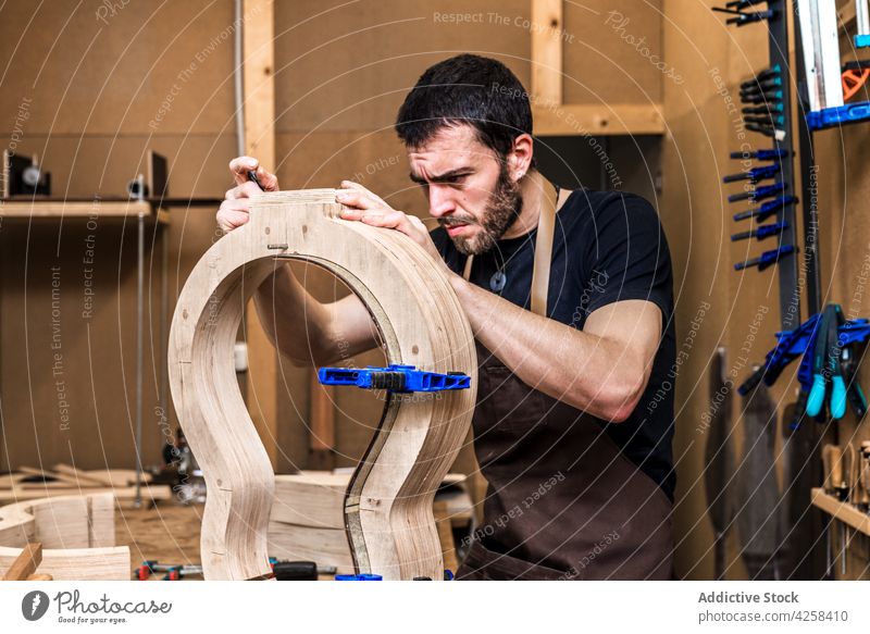 Luthier building guitar at table in workshop luthier accuracy precise profession skill man small business make musical instrument workroom clamp craftsman