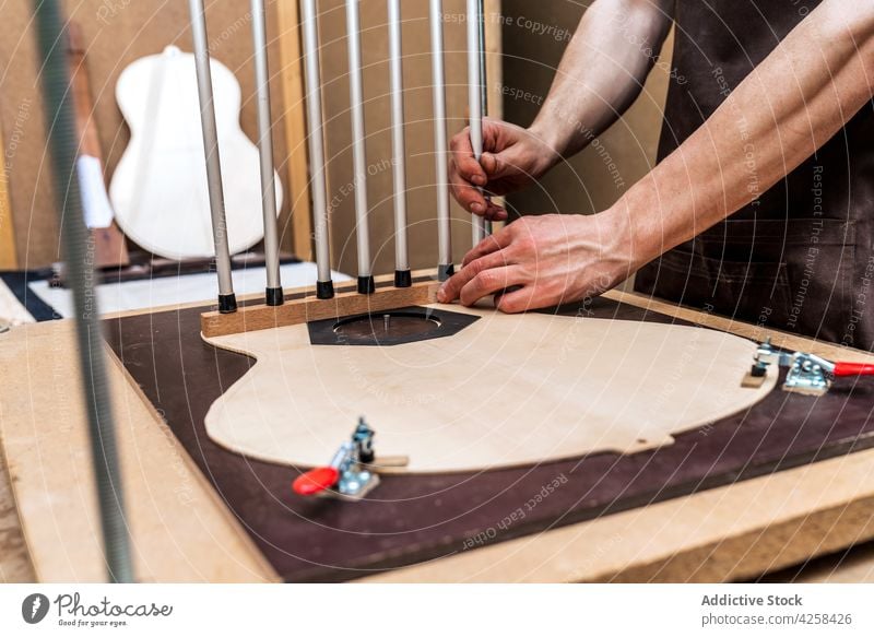 Craftsman installing metal sticks while building guitar in workroom luthier professional accuracy precise small business workshop artisan plank woodwork job