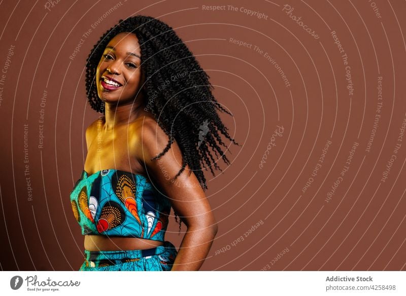 Black woman wearing colorful dress standing on floor peaceful grace feminine posture style afro individuality personality serene female long hair bright model