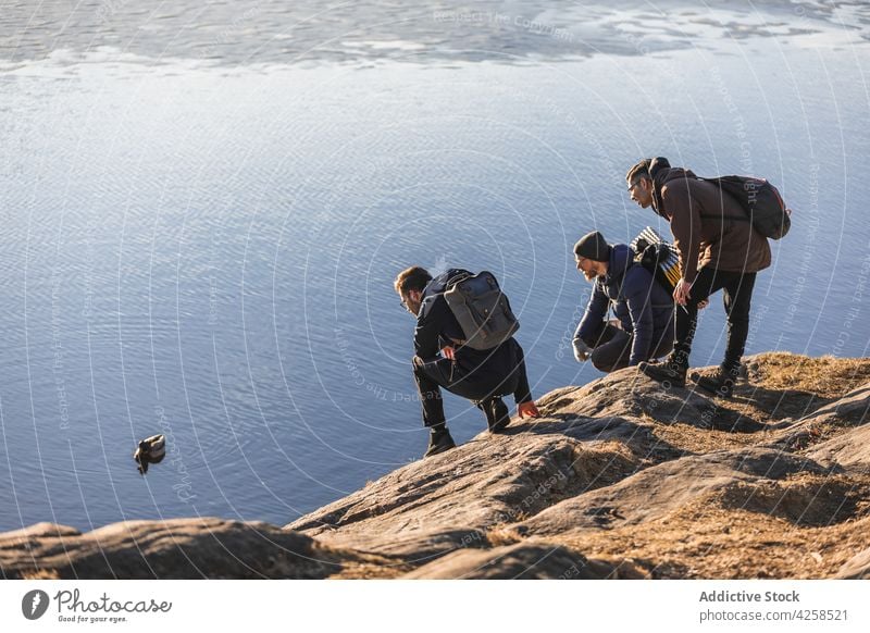 Young travelling guy looking at duck floating on lake water men admire mallard traveler hike journey bird watching friend together nature cliff vacation young