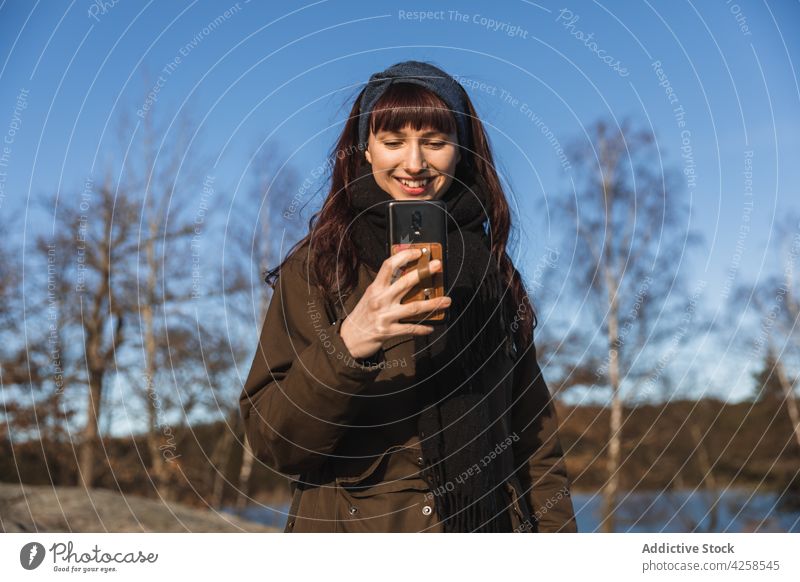 Smiling woman taking photo on smartphone using positive take photo memory smile nature autumn connection female cheerful glad optimist casual cellphone young