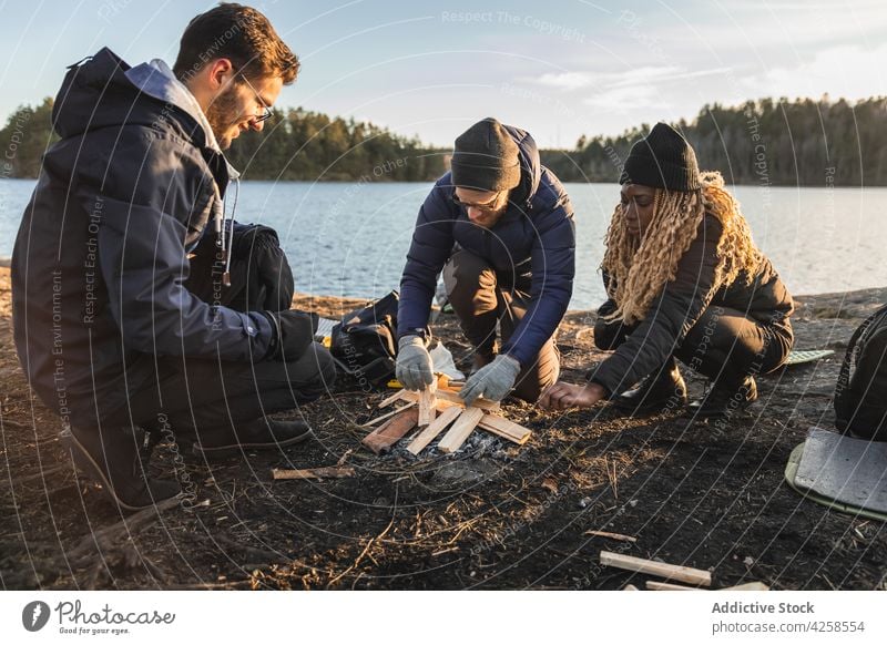 People in gloves preparing wood for bonfire men friend prepare campfire firewood environment fireplace log tourism adventure male together nature sit travel