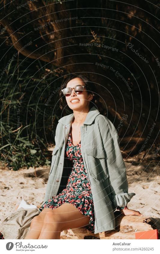 Woman smiling on the beach looking to camera while using sunglasses summer concept lifestyle curly hipster teenager female modern moroccan woman young