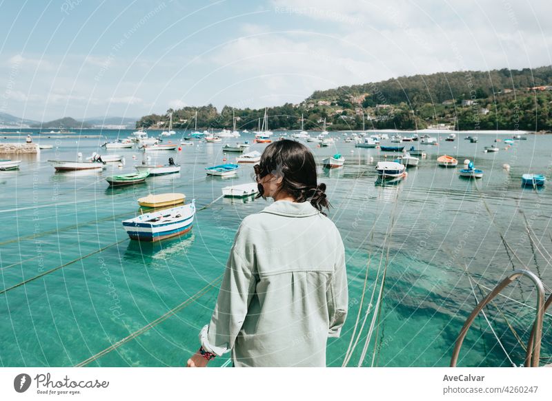 Woman backwards in front of the sea with a lot of boats during a sunny day person female portrait woman alone glamour joy sunlight yacht young brunette