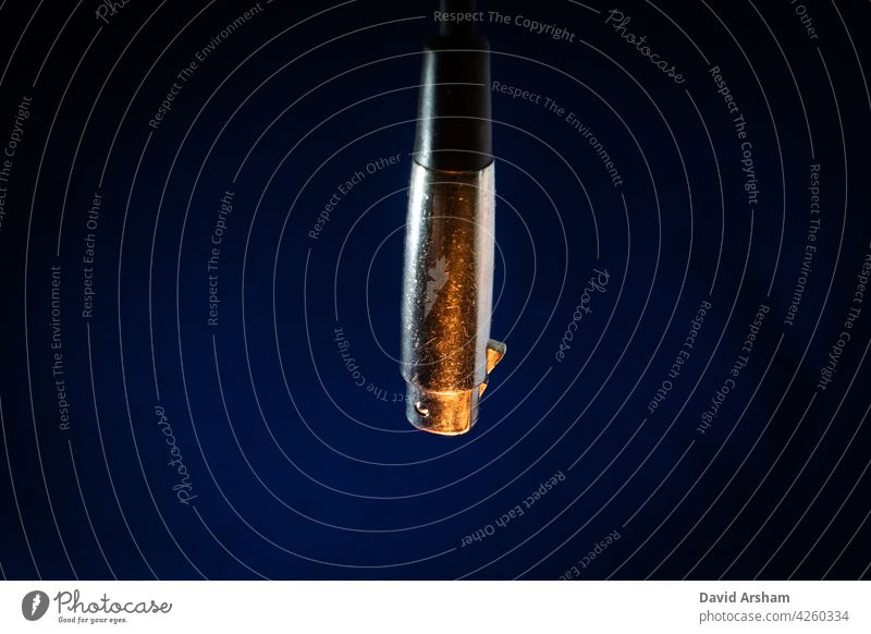 Closeup of Dangling Worn out and Scratched Male XLR Connector isolated on Blue Background with Orange Lighting jack xlr instrument cable audio cable cord