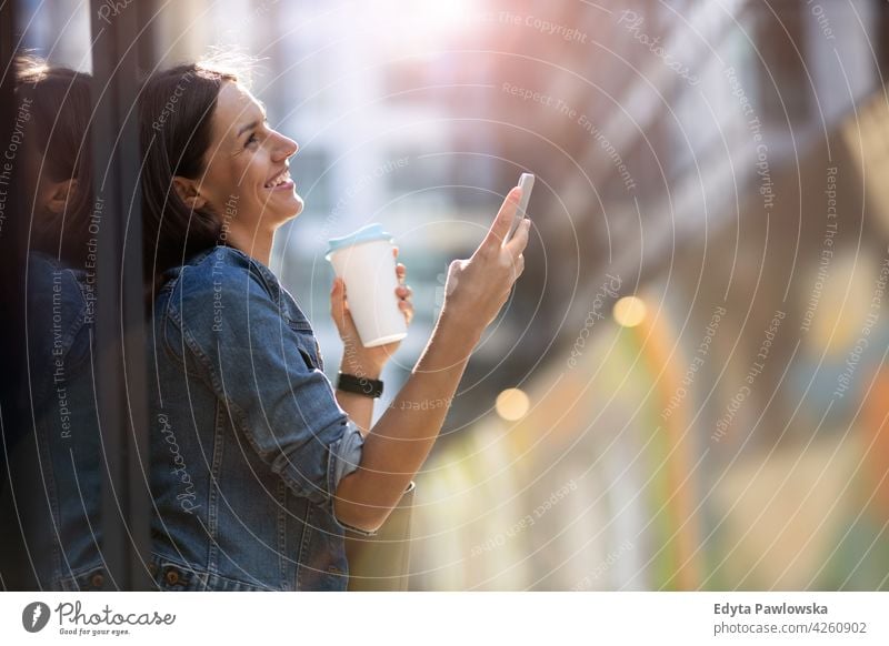 Young woman with smartphone in an urban city area street active people young adult casual attractive female happy Caucasian enjoying one person beautiful