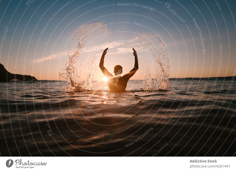 Unrecognizable sportsman in sea with splattering water in sunshine ocean arms raised splash nature seascape sky wavy sundown athlete mountain highland enjoy