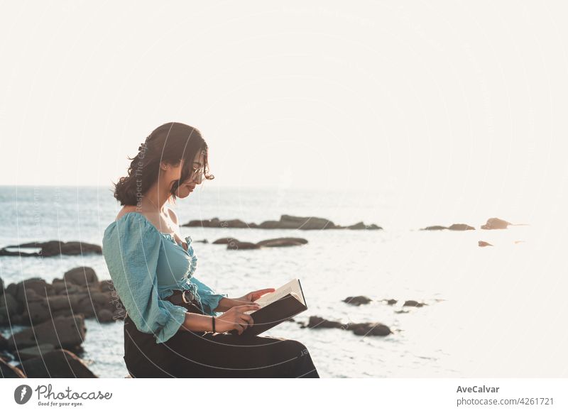 Young woman smiling to camera while reading at the beach during a super sunset while using a mask relax and inspirational concepts with copy space lifestyle colorful