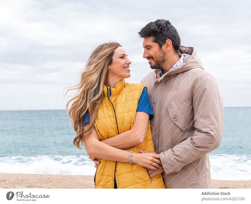 Content diverse couple embracing on sea coast embrace love relationship romantic spend time weekend content seashore portrait boyfriend girlfriend happy romance