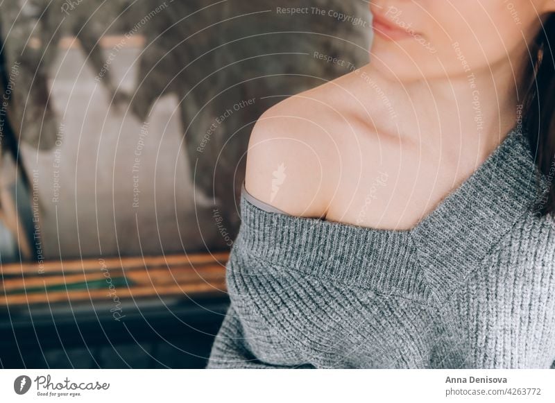 Close up off the shoulder with grey sweater off woman portrait young clavicle beautiful trendy cloth off female casual brunette table person adult attractive