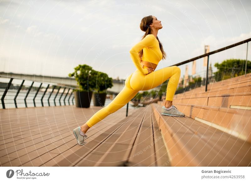 Young woman stretching on the riverside young jogging training fitness up female runner athlete people lifestyle healthy person body summer legs sportswear