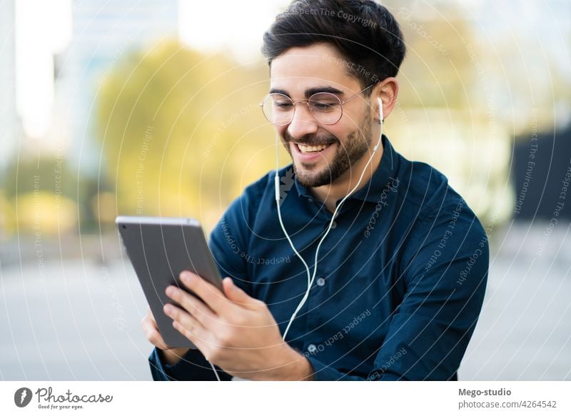 Young man using digital tablet outdoors. young technology mobile working social earphones network touchscreen outside online concept display wireless connection