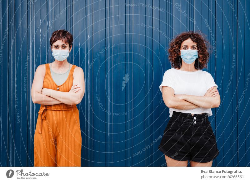 two caucasian women outdoors wearing face mask keeping social distance in Pandemic during corona virus elbow covid avoid prevention people generation safety