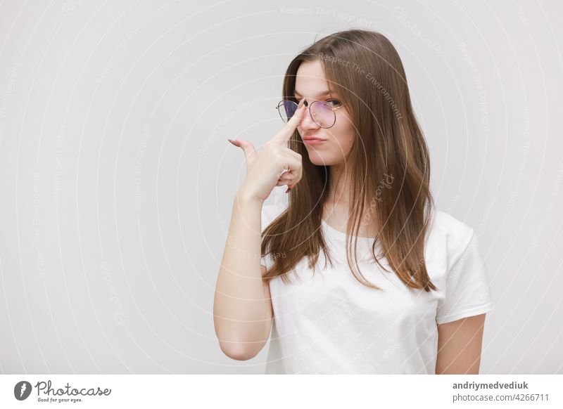 Focused frowning office girl staring at camera through eyeglasses on white background. Young woman adjusting eyewear. Glasses wearing concept business fashion