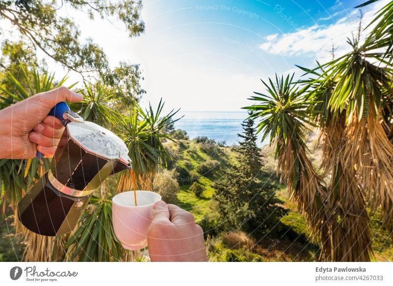 Hand Pouring Coffee In Cup against ocean, blue sky and exotic trees palm tropical island beautiful paradise palm tree beauty green garden coffee coffee cup