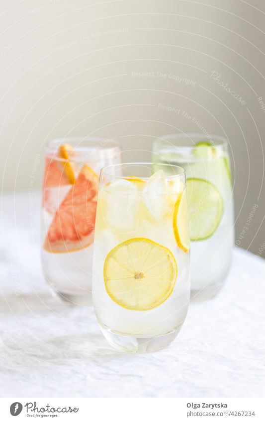 Three glasses with cold citrus water. drink lemonade ice grapefruit lime summer refreshment perspiration set beverage three white tablecloth minimal cocktail