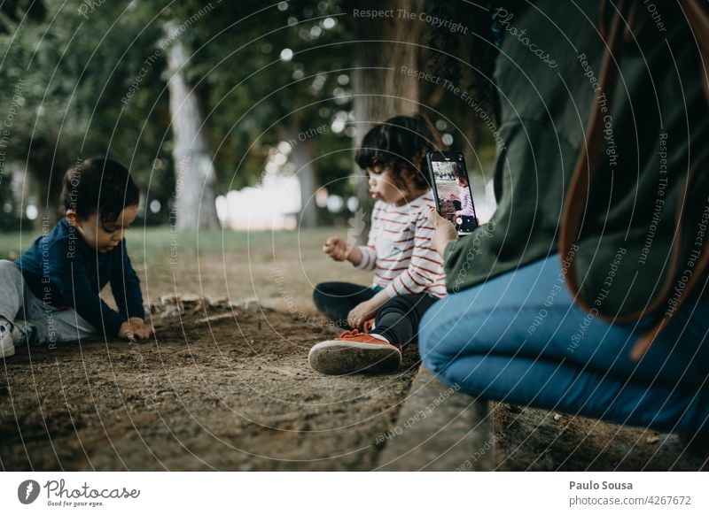 Mother photographing childrens playing Child childhood Brothers and sisters Mother with child soil Curiosity Photographic technology smartphone Technology Life