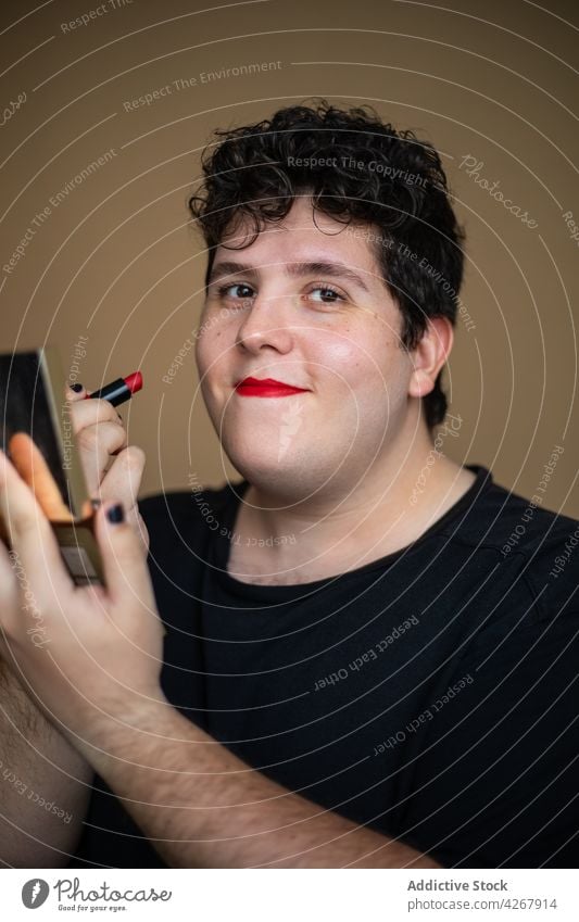 Overweight male with mirror applying red lipstick man cosmetic cosmetology transgender makeup visage androgynous queer extravagant transsexual unusual process