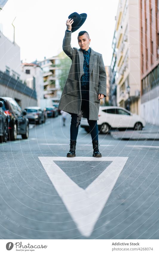 Androgynous person with hat on city road androgynous fashion style arm raised lgbtq lifestyle indicate arrow transsexual individuality identity accept mohawk