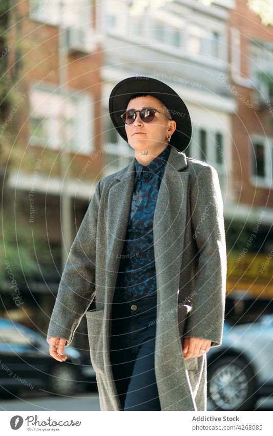 Queer in stylish outerwear and sunglasses outdoors transgender person style fashion individuality accept identity tattoo portrait queer androgynous sincere