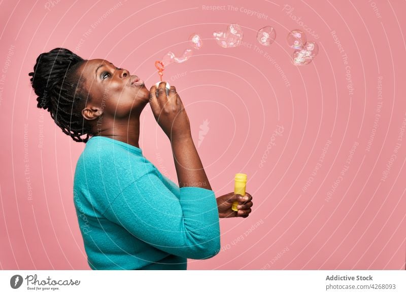 Joyful black woman blowing soap bubbles in studio ethnic joyful african american happy colorful vivid playful toy having fun smile entertain positive cheerful