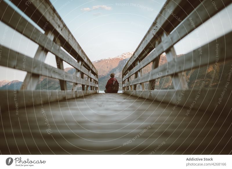 Tourist enjoying view from wooden boardwalk in highlands traveler lake admire mountain explore nature shore pond person tourism backpack journey landscape