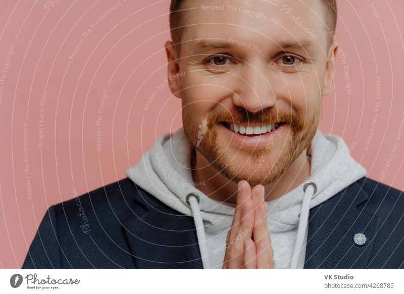 Happy man making praying gesture and smiling at camera handsome young stylish hope regretful expression making wish stubble good forgiveness religion