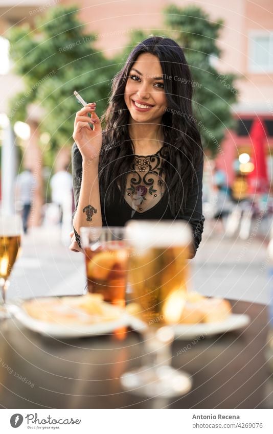 gorgeous Spanish woman smokes cigar and drinks beer on the terrace of a bar young attractive 20s joy people person youth urban women pretty pretty people