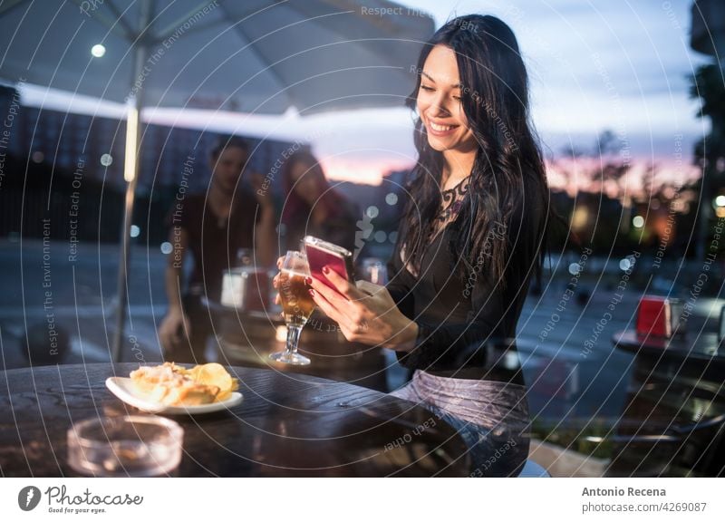 woman looking smartphone in bar terrace while drinking beer young attractive 20s joy people person youth urban women pretty pretty people outdoors city sit