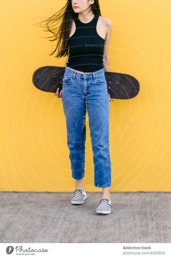 Anonymous skateboarder in casual apparel on pavement on yellow background skater cool contemporary generation spare time lifestyle teen equipment sport footwear