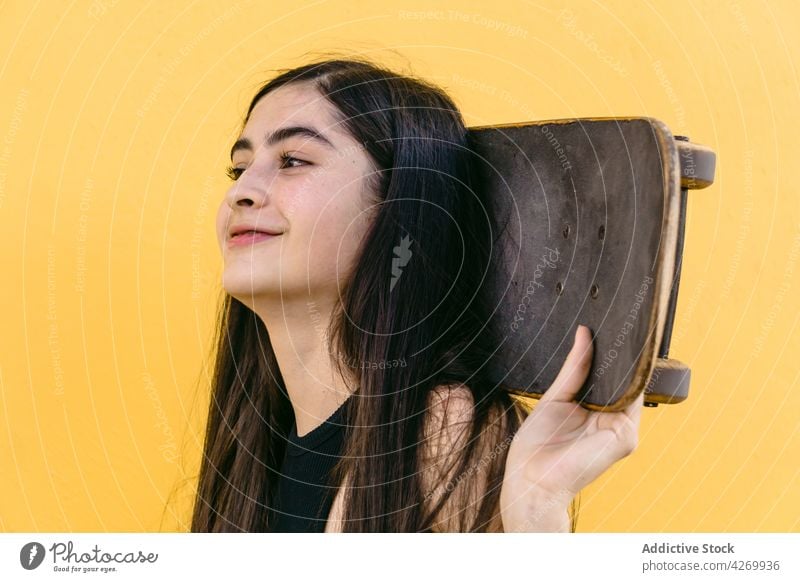 Smiling skater with skateboard on yellow background skateboarder smile sport friendly pleasant pastime weekend teenage portrait charming content contemporary