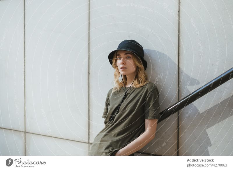 Millennial woman on stairs against concrete wall in town individuality style casual feminine gentle lifestyle urban tender romantic wistful dreamy contemplate