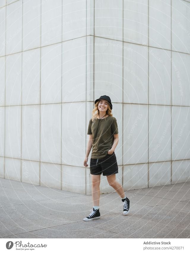 Happy woman walking over urban pavement against wall happy active having fun energy dynamic lifestyle city tile cheerful gumshoe modern stroll carefree street