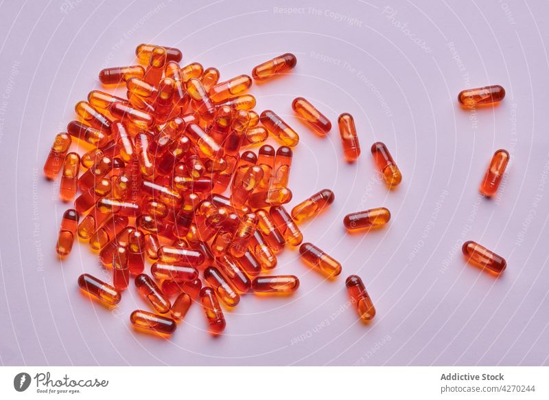 Orange pills scattered on pink surface drug medication capsule cure composition orange remedy vitamin treat pharmacy health care concept colorful pharmaceutical