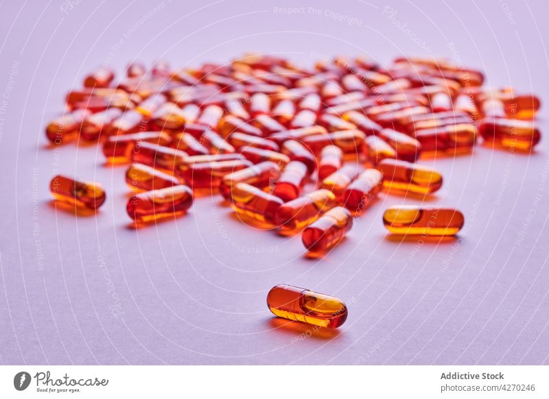 Orange pills scattered on pink surface drug medication capsule cure composition orange remedy vitamin treat pharmacy health care concept colorful pharmaceutical